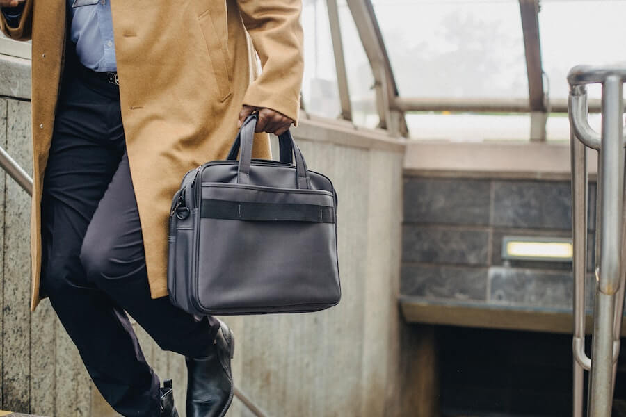 person walking up staircase with black suitcase on sabbatical leave