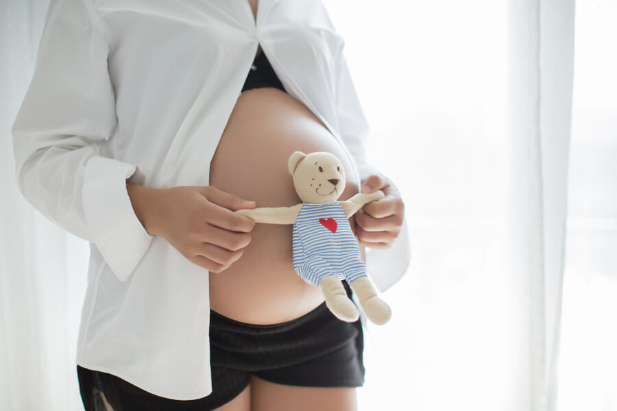 pregnant woman holding teddy bear for child