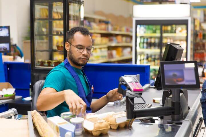 male cashier scanning products at till