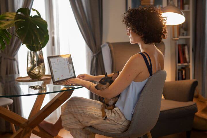 woman working from home comfortably with dog in lap